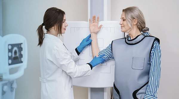 a healthcare worker taking an X-ray of a patient’s arm after completing limited scope radiography training
